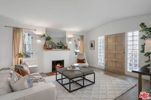 living room featuring vaulted ceiling, light wood-type flooring, and brick ceiling