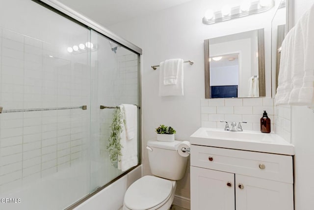 full bathroom featuring toilet, vanity, shower / bath combination with glass door, and tasteful backsplash