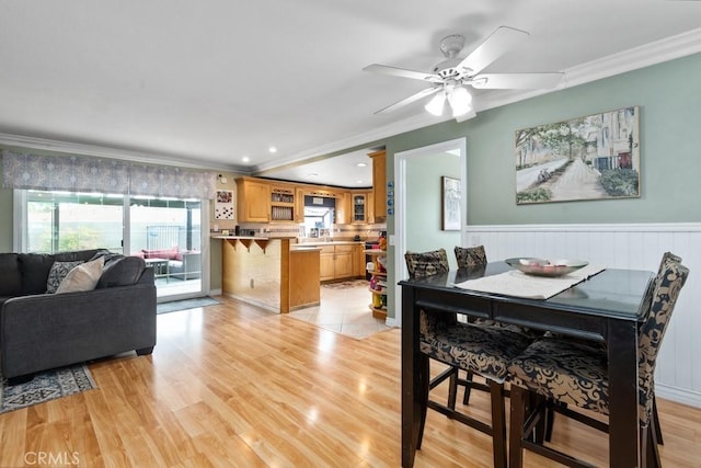 dining room with crown molding, ceiling fan, and light hardwood / wood-style flooring