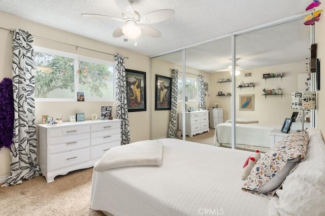 bedroom featuring ceiling fan, light colored carpet, a closet, and a textured ceiling