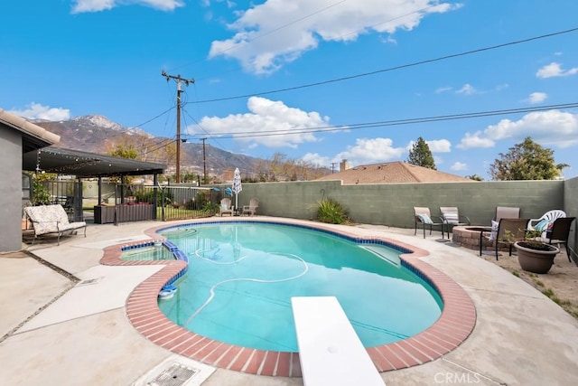 view of pool featuring a patio, a mountain view, and a diving board