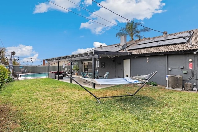 rear view of house featuring central AC unit, a pergola, a lawn, and solar panels