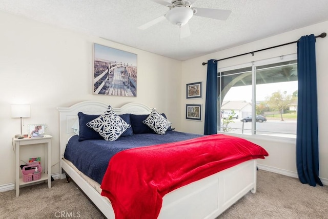 bedroom with ceiling fan, carpet, and a textured ceiling