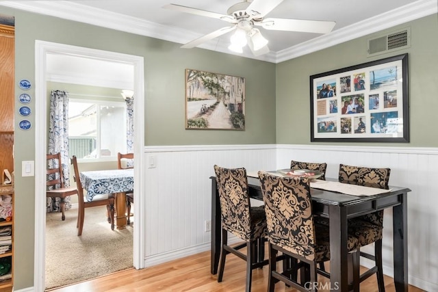 dining area featuring wood-type flooring, ornamental molding, and ceiling fan