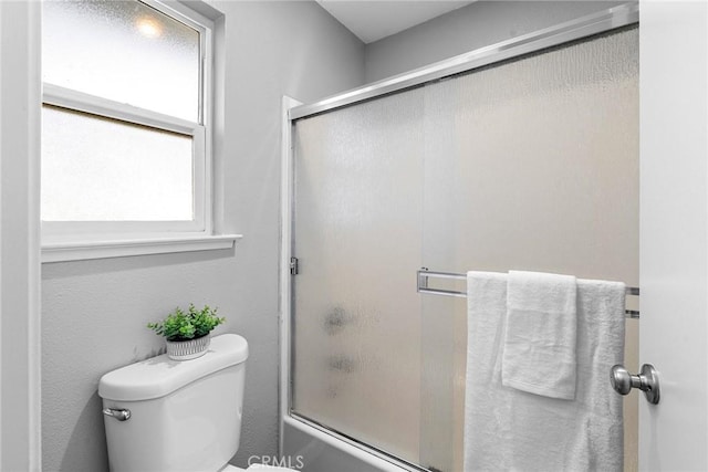 bathroom with toilet and bath / shower combo with glass door