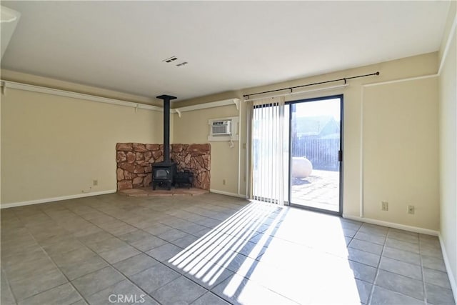 unfurnished living room featuring a wood stove, a wall mounted AC, and light tile patterned floors