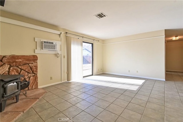 foyer with an AC wall unit, a wood stove, and light tile patterned flooring