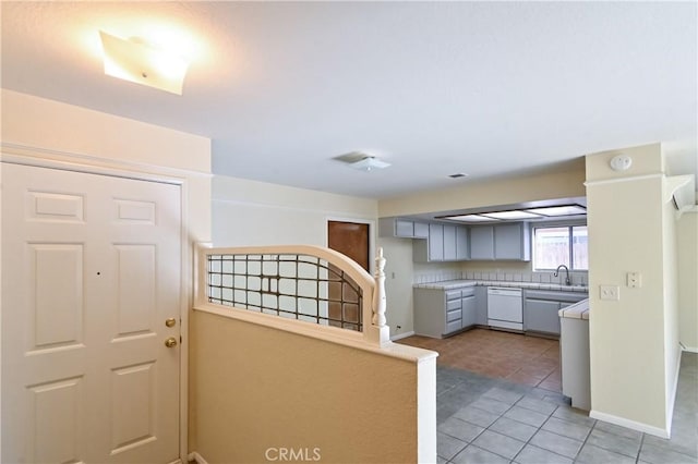 kitchen featuring white dishwasher, sink, tile patterned floors, and gray cabinets