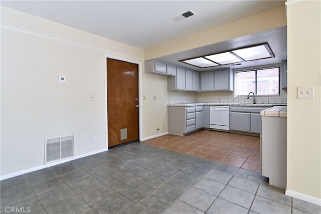 kitchen with sink, gray cabinets, tile patterned flooring, and dishwasher