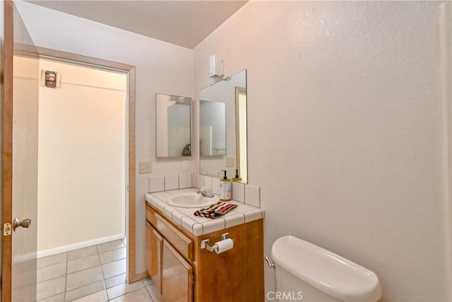 bathroom with toilet, tile patterned flooring, and vanity