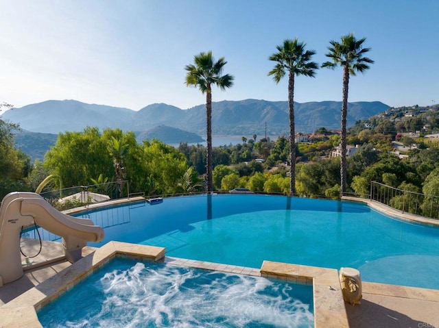 view of pool with a mountain view, an in ground hot tub, and a water slide