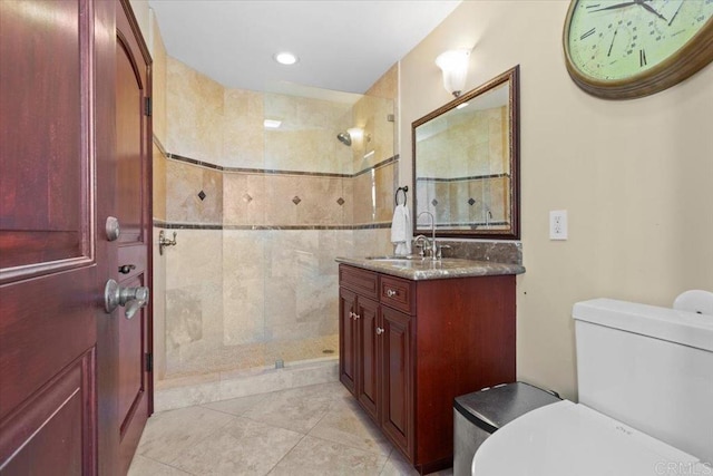 bathroom with tile patterned floors, tiled shower, vanity, and toilet