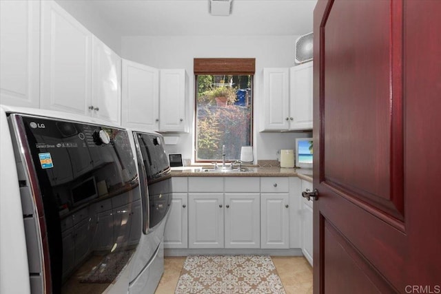 clothes washing area with sink, washer and clothes dryer, light tile patterned floors, and cabinets