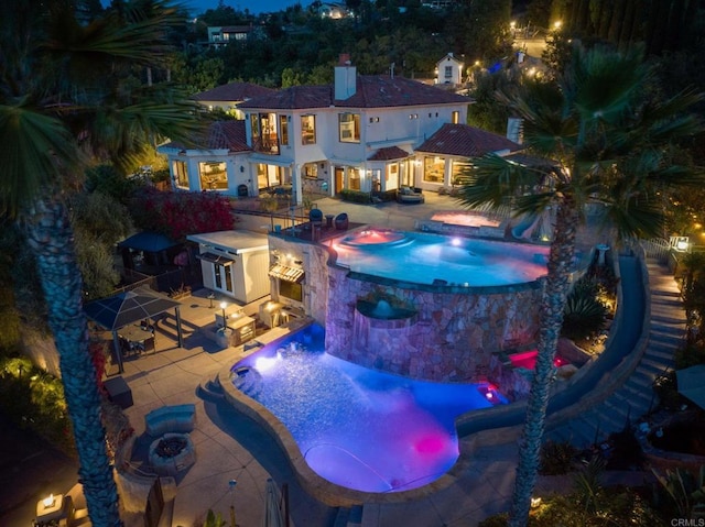 view of swimming pool featuring an in ground hot tub, a patio area, exterior kitchen, and a fire pit