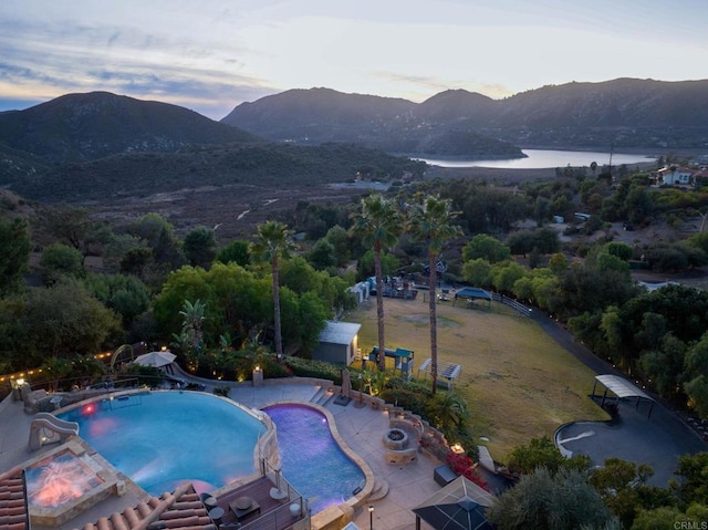 pool at dusk featuring a patio area and a water and mountain view