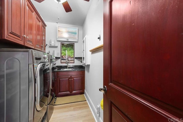 clothes washing area featuring washer and dryer, cabinets, sink, ceiling fan, and light hardwood / wood-style flooring