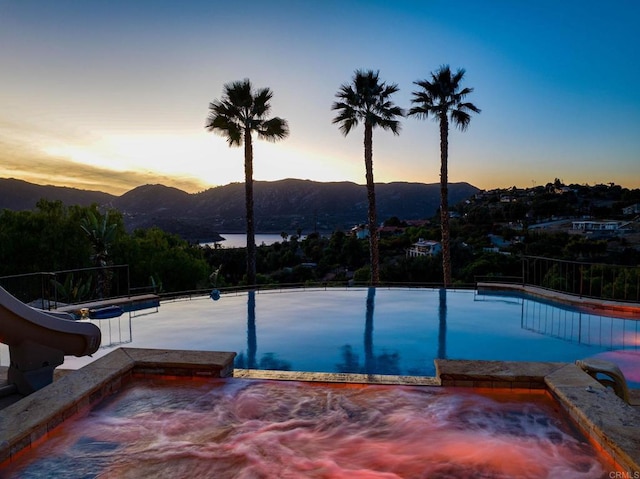 pool at dusk with a water and mountain view and a water slide