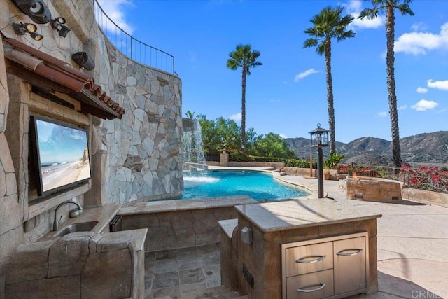 view of pool with a mountain view, a patio, pool water feature, and sink