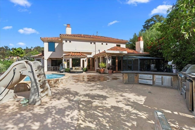 rear view of property with exterior kitchen and a patio