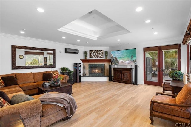 living room featuring crown molding, a tray ceiling, light hardwood / wood-style floors, and french doors