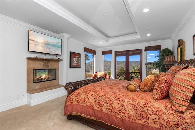 carpeted bedroom with french doors, a fireplace, crown molding, and a raised ceiling