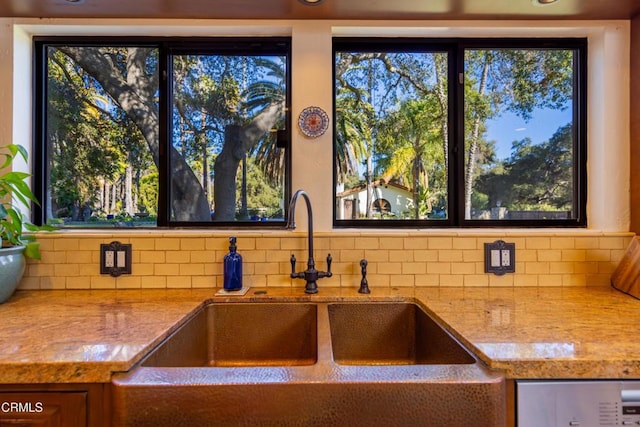 kitchen with tasteful backsplash, sink, and light stone counters