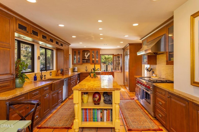 kitchen with ventilation hood, sink, premium appliances, a center island, and light stone countertops