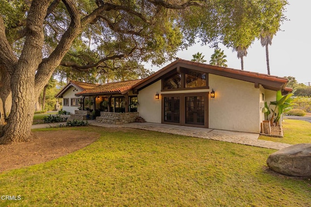 back of property with a lawn, a patio area, and french doors