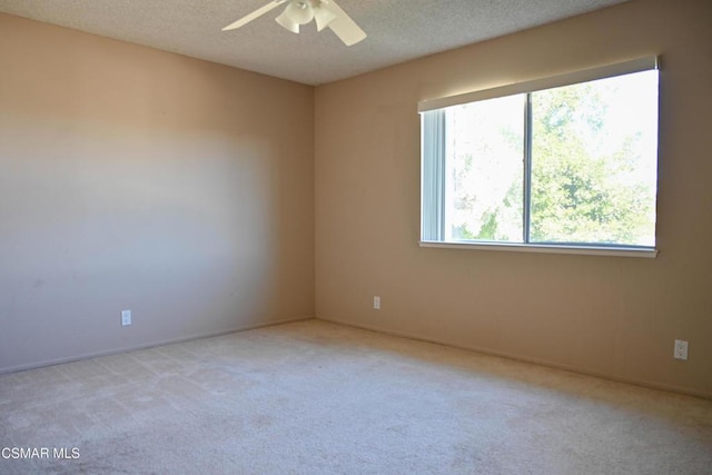 empty room featuring ceiling fan, light colored carpet, and a textured ceiling