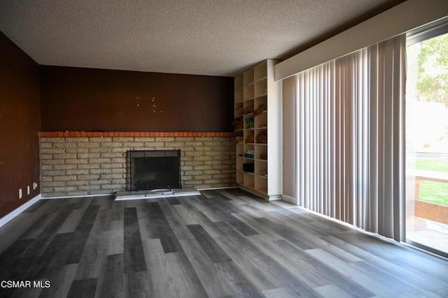 unfurnished living room with hardwood / wood-style flooring, a brick fireplace, built in features, and a textured ceiling