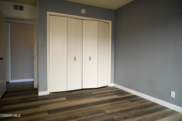 unfurnished bedroom with dark wood-type flooring and a closet