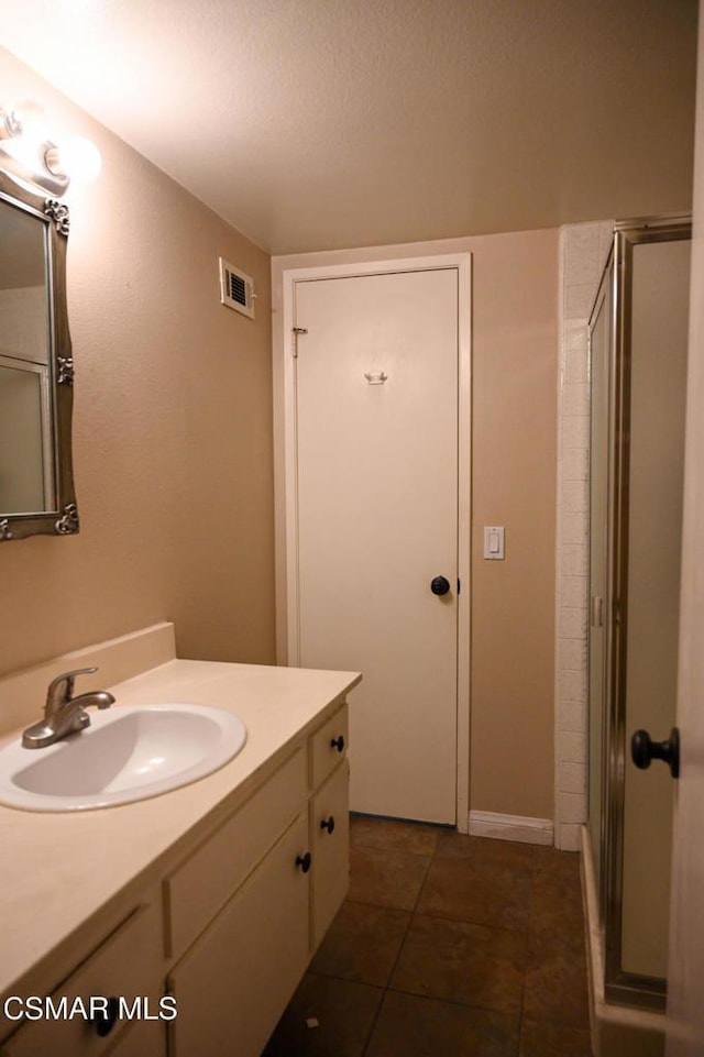 bathroom featuring tile patterned flooring, vanity, and an enclosed shower