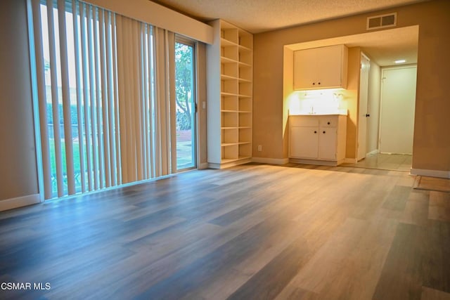 spare room with a textured ceiling and light hardwood / wood-style floors