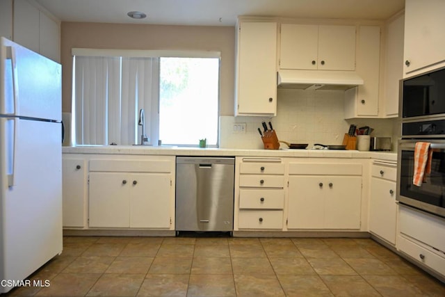 kitchen with appliances with stainless steel finishes, sink, white cabinets, backsplash, and light tile patterned floors