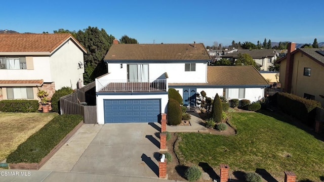 view of front of home with a garage, a front lawn, and a balcony