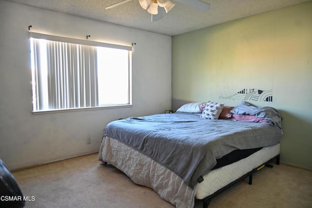 carpeted bedroom with ceiling fan and a textured ceiling