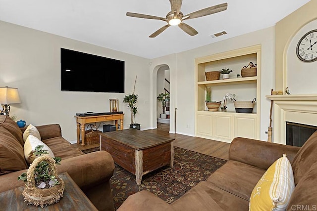 living room featuring hardwood / wood-style floors, built in features, and ceiling fan