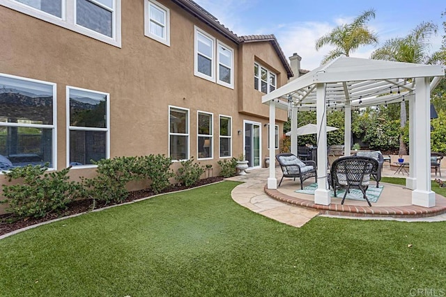 rear view of house with a yard, a pergola, and a patio