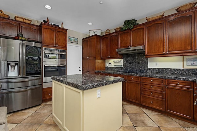 kitchen featuring a center island, light tile patterned floors, appliances with stainless steel finishes, dark stone counters, and decorative backsplash