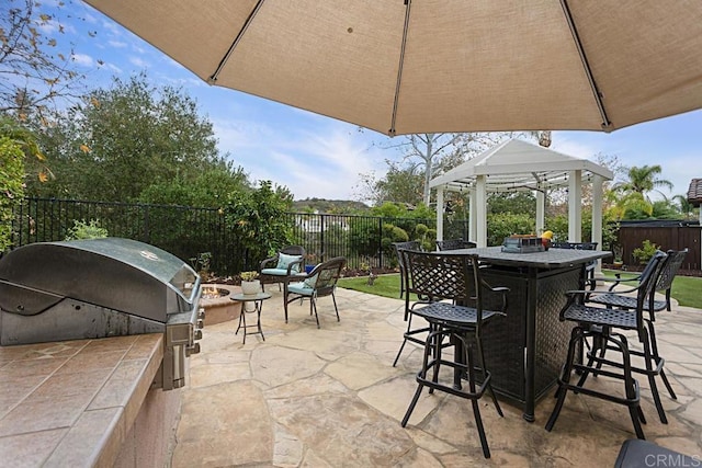 view of patio / terrace featuring a bar, grilling area, exterior kitchen, and a gazebo