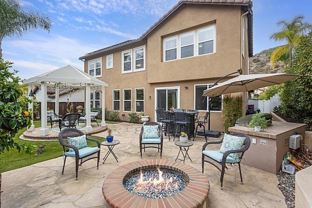 back of property with a fire pit, a patio, and a gazebo