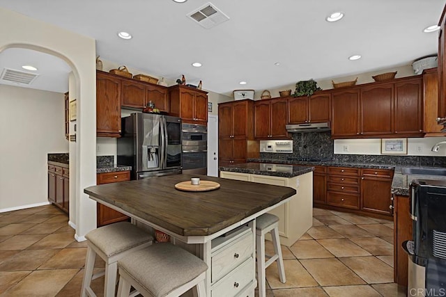 kitchen with sink, stainless steel fridge, a center island, a kitchen bar, and black electric cooktop