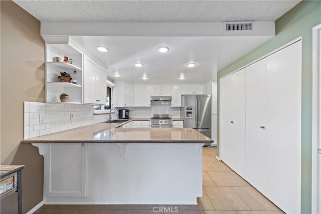 kitchen featuring light stone countertops, white cabinets, stainless steel appliances, sink, and kitchen peninsula