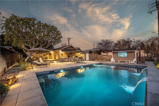 pool at dusk featuring a patio area and pool water feature