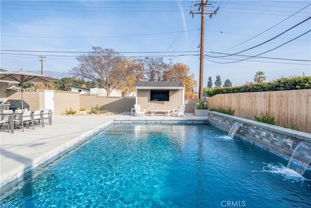 view of pool with a patio area, an outdoor structure, and pool water feature