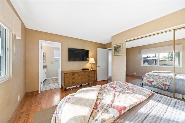 bedroom featuring hardwood / wood-style flooring, a closet, and ensuite bath