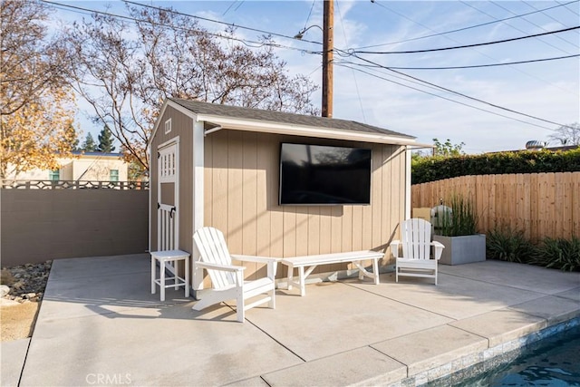 view of patio featuring a fenced in pool and an outbuilding