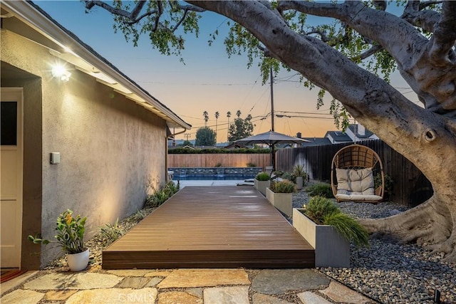 deck at dusk featuring a pool