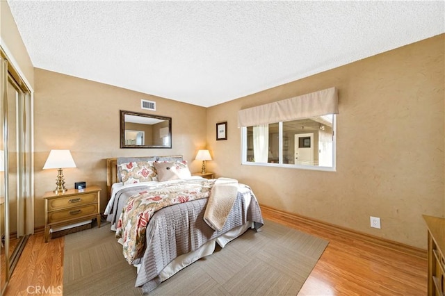 bedroom with a closet, hardwood / wood-style floors, and a textured ceiling