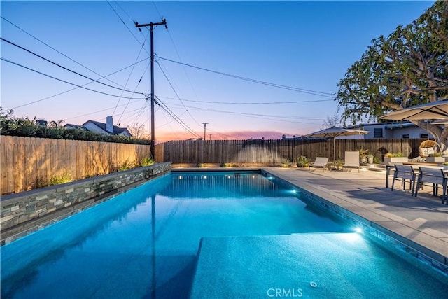 pool at dusk with a patio area